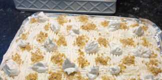 Ένα κομμάτι από ραβανί με στρώσεις κρέμας βανίλιας και σαντιγί, πασπαλισμένο με καρύδι.