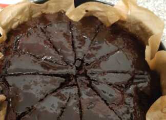 Ζεστή σοκολατόπιτα ταψιού, βαθιά καφέ, με υγρή και λαμπερή επιφάνεια από το σιρόπι, χαραγμένη σε τετράγωνα κομμάτια.