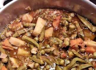 Μια κατσαρόλα γεμάτη με κοκκινιστό κοτόπουλο και μπάμιες σε πλούσια κόκκινη σάλτσα.