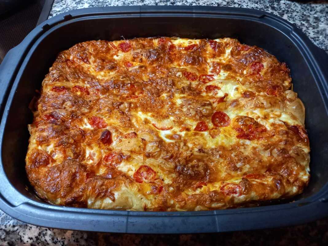 patsavouroturopita Η πίτα μέσα στη γάστρα, έτοιμη για ψήσιμο, με τα σουρωτά φύλλα και τα ντοματίνια