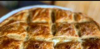 Μια στρογγυλή, χρυσαφένια πρασόπιτα με σπιτικό φύλλο, κομμένη σε κομμάτια, έτοιμη για σερβίρισμα.