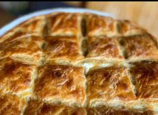 Μια στρογγυλή, χρυσαφένια πρασόπιτα με σπιτικό φύλλο, κομμένη σε κομμάτια, έτοιμη για σερβίρισμα.