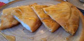 Πιάτο με μία Σφακιανή πίτα, περιχυμένη με μέλι και σουσάμι, έτοιμη να την απολαύσετε