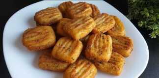 Ένα πιάτο γεμάτο χρυσαφένιες, τηγανισμένες κροκέτες πατάτας, πασπαλισμένες με ψιλοκομμένο μαϊντανό.