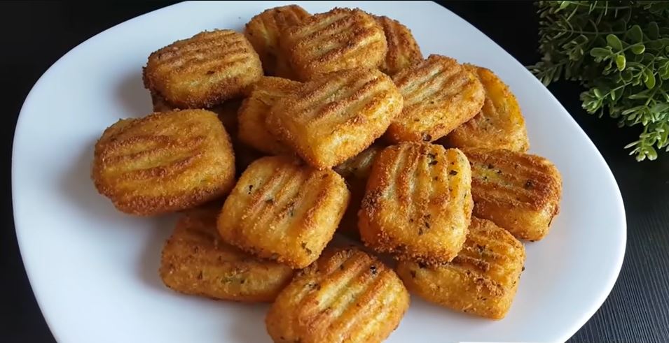 tiganitesPatatesPane Ένα πιάτο γεμάτο χρυσαφένιες, τηγανισμένες κροκέτες πατάτας, πασπαλισμένες με ψιλοκομμένο μαϊντανό.