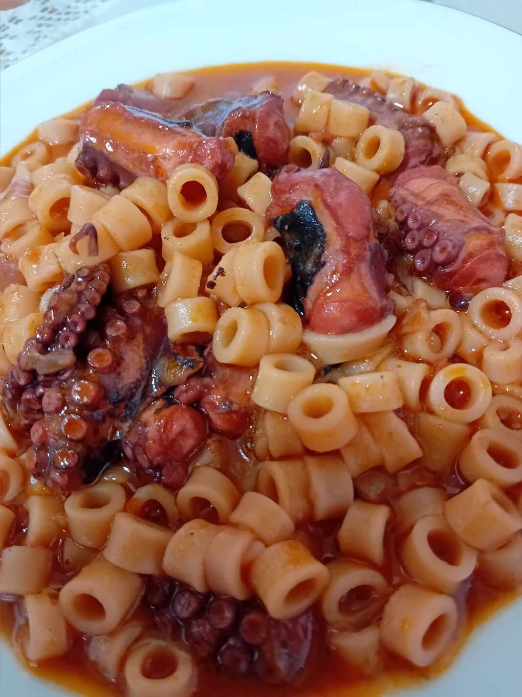 Παραδοσιακό χταπόδι με κοφτό μακαρονάκι σε πιάτο, κοκκινιστό με πλούσια σάλτσα.