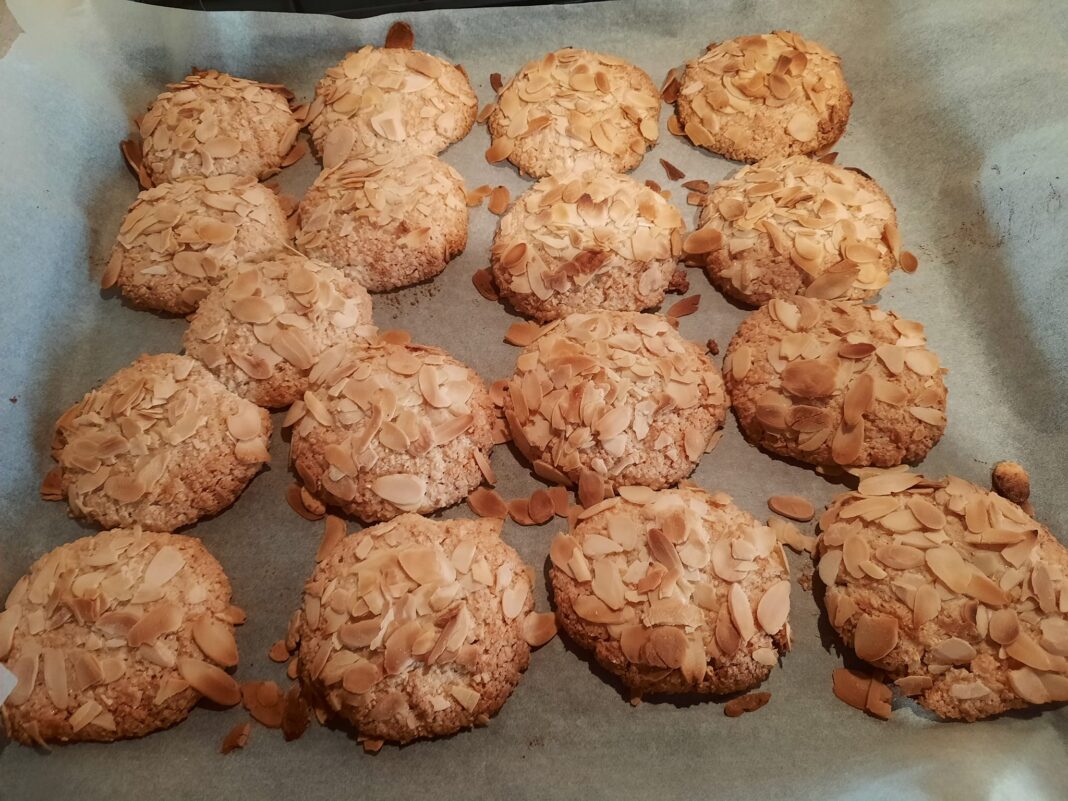 Ένα ταψί με φρεσκοψημένα αμυγδαλωτά, με φιλέ αμυγδάλου στην επιφάνεια.