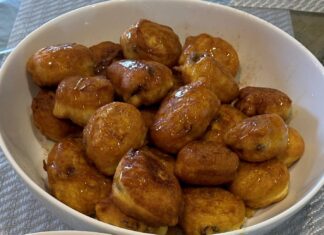 Ένα πιάτο γεμάτο με χρυσαφένιες Τηγανίτες με Σταφίδες, πασπαλισμένες με μέλι και κανέλα