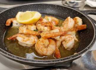 Ένα τηγάνι γεμάτο χρυσαφένιες, τηγανητές γαρίδες, μερικές από τις οποίες είναι κομμένες και δείχνουν την εσωτερική τους σάρκα.