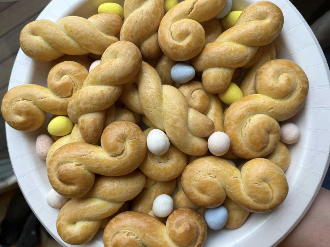 Πολλά χρυσαφένια κουλουράκια πορτοκαλιού σε ταψί ή σε πιατέλα, με μερικά πασπαλισμένα με σουσάμι.