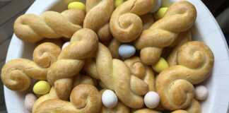 Πολλά χρυσαφένια κουλουράκια πορτοκαλιού σε ταψί ή σε πιατέλα, με μερικά πασπαλισμένα με σουσάμι.