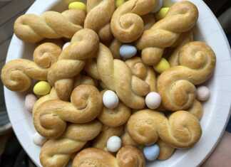 Πολλά χρυσαφένια κουλουράκια πορτοκαλιού σε ταψί ή σε πιατέλα, με μερικά πασπαλισμένα με σουσάμι.