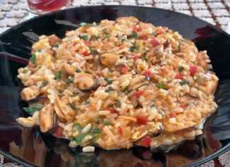 Πολίτικο μυδοπίλαφο σε πιάτο, με χυλωμένο ρύζι, κόκκινη σάλτσα, φρέσκο μαϊντανό και μερικά μύδια με το κέλυφος.