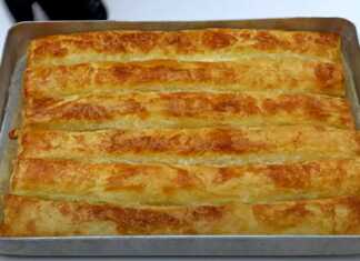 Χρυσαφένια ρολά τυρόπιτας τοποθετημένα δίπλα-δίπλα στο ταψί, με τραγανό φύλλο κρούστας που σπάει και πλούσια λιωμένη φέτα να ξεπροβάλλει.