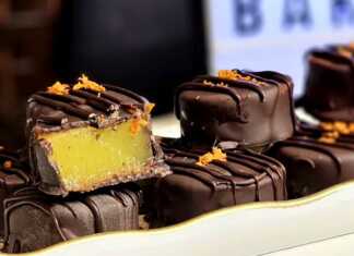 Χειροποίητα στρογγυλά σοκολατάκια καλυμμένα με μαύρη κουβερτούρα και στολισμένα με φρέσκο ξύσμα πορτοκαλιού πάνω σε λαδόκολλα