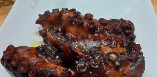 Κομμάτια χταποδιού σε ένα πιάτο, περιχυμένα με σκούρα κόκκινη σάλτσα κρασιού, γαρνιρισμένα με φρέσκο μαϊντανό.