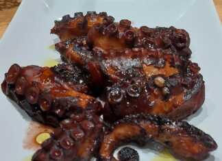 Κομμάτια χταποδιού σε ένα πιάτο, περιχυμένα με σκούρα κόκκινη σάλτσα κρασιού, γαρνιρισμένα με φρέσκο μαϊντανό.