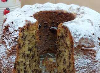 Αφράτο στρογγυλό κέικ πορτοκάλι νηστίσιμο, πασπαλισμένο με ζάχαρη άχνη, με εμφανή τα κομμάτια σοκολατένιας τρούφας.