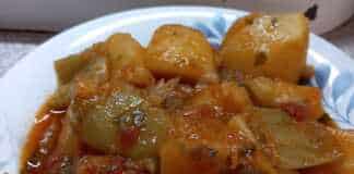 Ένα πιάτο με πατάτες γιαχνί και πολύχρωμα λαχανικά σε πλούσια κόκκινη σάλτσα.