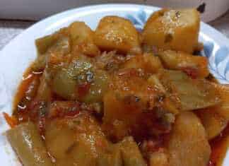 Ένα πιάτο με πατάτες γιαχνί και πολύχρωμα λαχανικά σε πλούσια κόκκινη σάλτσα.