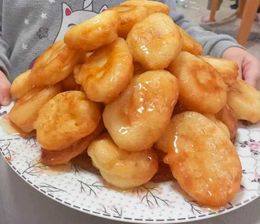 Χρυσαφένιες παραδοσιακές τηγανίτες σερβιρισμένες με μπόλικο μέλι και κανέλα σε ένα ρουστίκ πιάτο