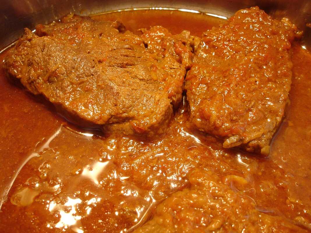 Ένα λαχταριστό πιάτο χοιρινό κατσαρόλας με σάλτσα ντομάτας σερβιρισμένο σε πιάτο.