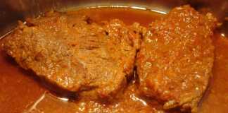 Ένα λαχταριστό πιάτο χοιρινό κατσαρόλας με σάλτσα ντομάτας σερβιρισμένο σε πιάτο.