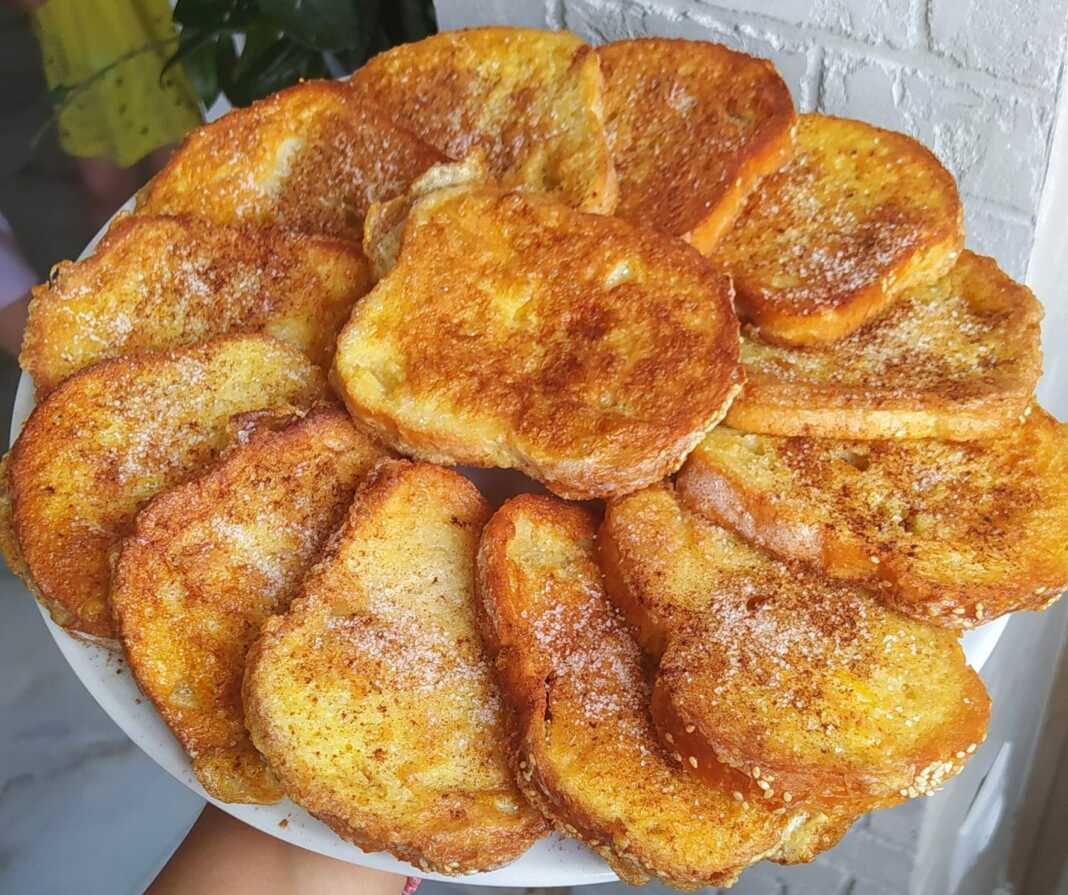 Ζεστές αυγοφέτες πασπαλισμένες με ζάχαρη και κανέλα σε ένα πιάτο.