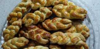 Πιάτο γεμάτο με αφράτα κουλουράκια πορτοκαλιού, με χρυσαφένια επικάλυψη από κρόκο αυγού.