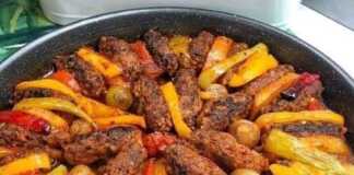 Ένα ταψί με ψημένα μπιφτέκια σε σειρά, εναλλάξ με φέτες από πατάτες, πιπεριές, κρεμμύδια και ντομάτες, όλα με ωραίο χρυσαφένιο χρώμα.