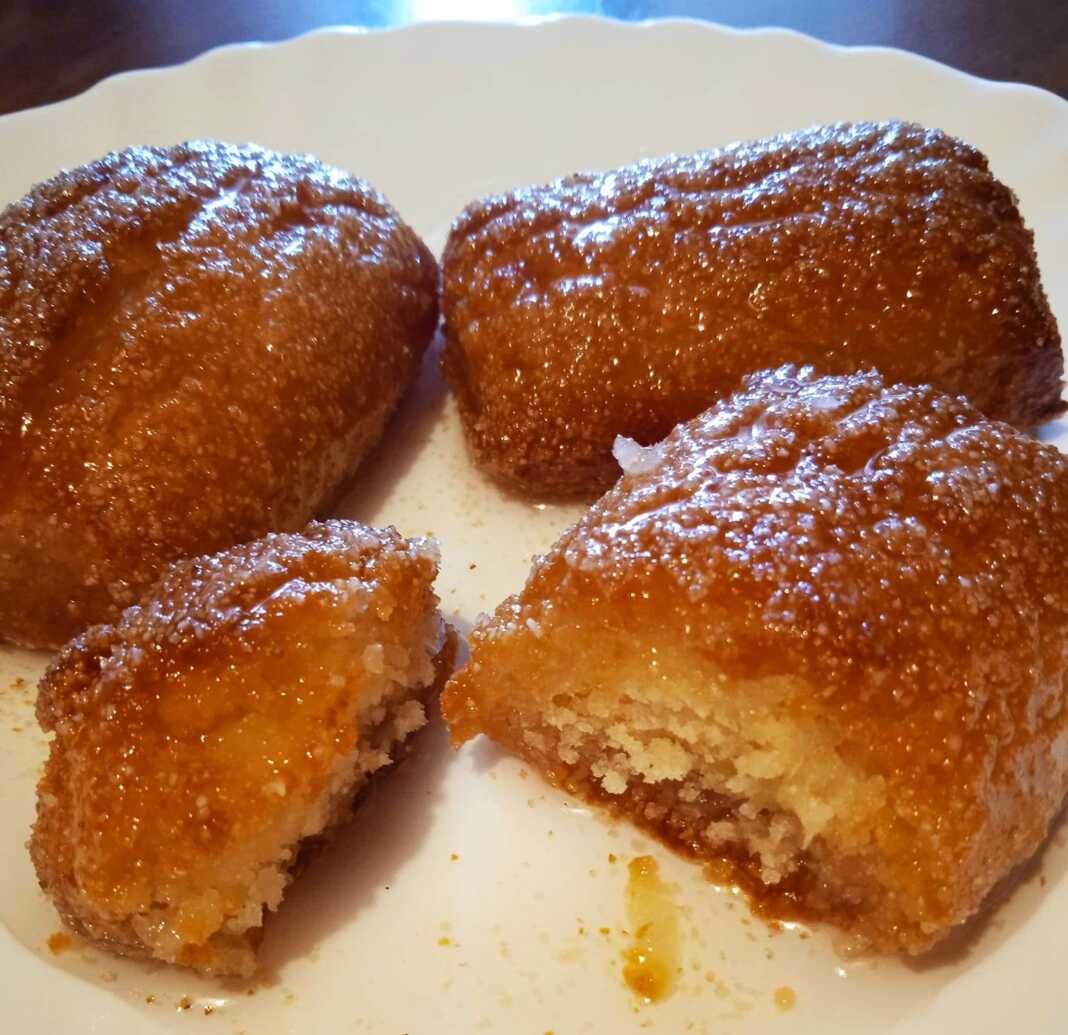 Μια πιατέλα με σιροπιαστά, στρογγυλά μπισκότα καρύδας, πασπαλισμένα με τριμμένη καρύδα.