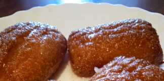 Μια πιατέλα με σιροπιαστά, στρογγυλά μπισκότα καρύδας, πασπαλισμένα με τριμμένη καρύδα.