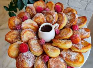 Στοίβα από χρυσαφένιες αφράτες τηγανίτες με γιαούρτι περιχυμένες με μέλι και πασπαλισμένες με καρύδια σε ένα λευκό πιάτο