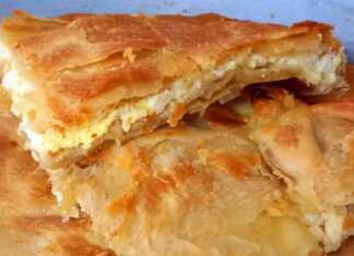 Χρυσαφένια παραδοσιακή τυρόπιτα με χωριάτικο φύλλο κομμένη σε κομμάτια μέσα στο ταψί