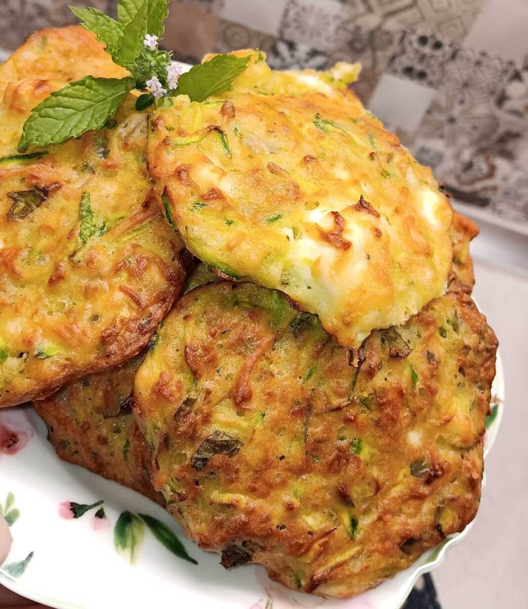 Ένα πιάτο γεμάτο με χρυσαφένιους, στρογγυλούς κολοκυθοκεφτέδες, φρεσκοψημένους, πάνω σε λαδόκολλα.