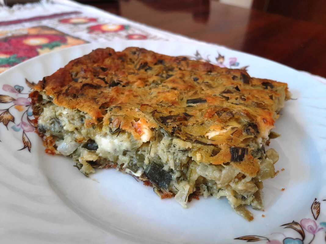 Μια χρυσαφένια πρασοτυρόπιτα χωρίς φύλλο σε ένα ταψί.