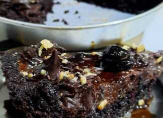 Μια φέτα από τάρτα σοκολάτας με πλούσια καφέ κρέμα, βάση παντεσπανιού και γαρνιρισμένη με λαμπερά κόκκινα βύσσινα.