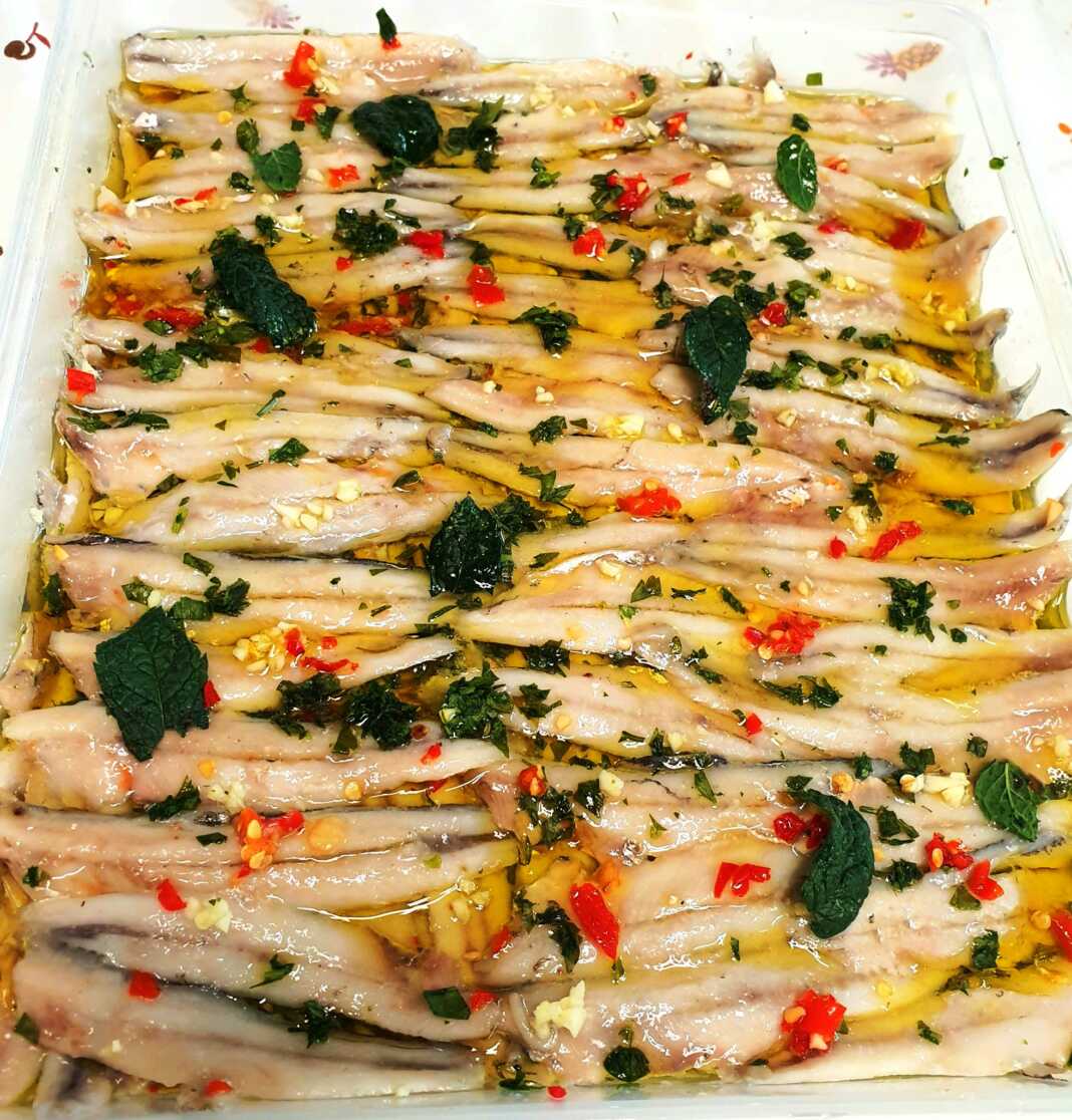 gavros-Marinatos Πιάτο με φρεσκομαριναρισμένο γαύρο, γαρνιρισμένο με ψιλοκομμένο μαϊντανό, πιπεριά και φέτες λεμονιού.