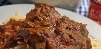 Κοκκινιστό Μοσχάρι με Μακαρόνια σε πιάτο, με τριμμένο τυρί και πλούσια σάλτσα.