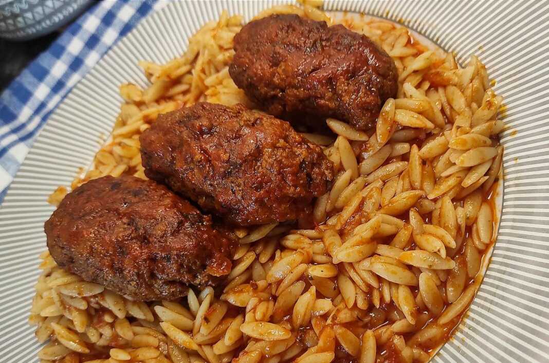 Μελωμένο Γιουβέτσι με Κεφτέδες, σερβιρισμένο σε πιάτο, με τριμμένο τυρί.