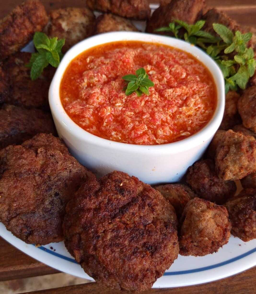 Τηγανητοί κεφτέδες σερβιρισμένοι δίπλα σε πικάντικη στραπατσάδα με ντομάτα και πιπεριά.