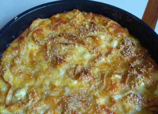 Τετράγωνο κομμάτι ψευτόπιτας με τορτίγιες, πασπαλισμένο με σουσάμι, με την επιφάνειά του να έχει ροδίσει και να φαίνονται τα λιωμένα τυριά.