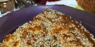 Τυρόπιτα με γιαούρτι, κομμένη σε κομμάτια, με χρυσαφένια κρούστα και σουσάμι.