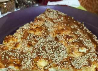 Τυρόπιτα με γιαούρτι, κομμένη σε κομμάτια, με χρυσαφένια κρούστα και σουσάμι.