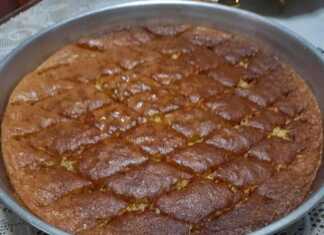 Ένα ταψί από σιροπιαστή Μελαχρινή με τριμμένο καρύδι στην επιφάνεια, σερβιρισμένο σε λευκό πιάτο.