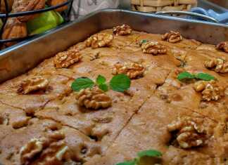 Κέικ με μήλα και καρύδι, πασπαλισμένο με ζάχαρη άχνη, κομμένο σε τετράγωνα κομμάτια.