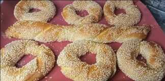 Στριφτά κουλούρια Θεσσαλονίκης με άφθονο σουσάμι, σερβιρισμένα σε ξύλινη επιφάνεια.