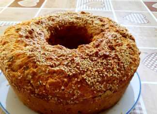 Μια ψημένη τυρόπιτα σε στρογγυλή φόρμα κέικ με χρυσαφένια κρούστα και αρώματα από δυόσμο