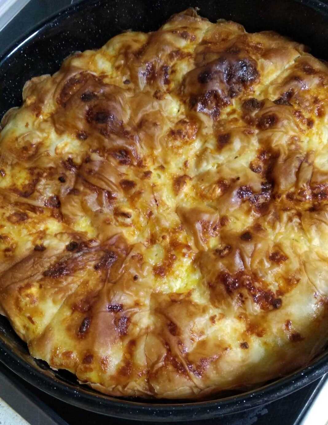 Παραδοσιακή βασιλόπιτα τυρόπιτα με σπιτικό φύλλο, κομμένη σε κομμάτια, με χρυσαφένια κρούστα.