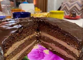 Πολύφωτη σοκολατένια τούρτα "Πράγα" με γυαλιστερό γλάσο σοκολάτας, κομμένη σε φέτες, αποκαλύπτοντας τις στρώσεις του σκούρου παντεσπανιού και της κρέμας.